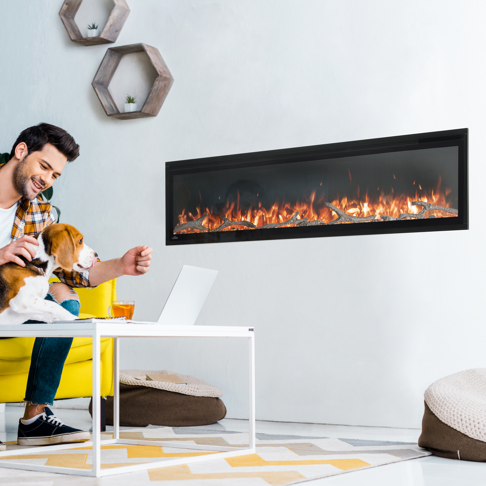 Man sitting on a yellow couch with a dog, next to a modern electric fireplace in a living room.