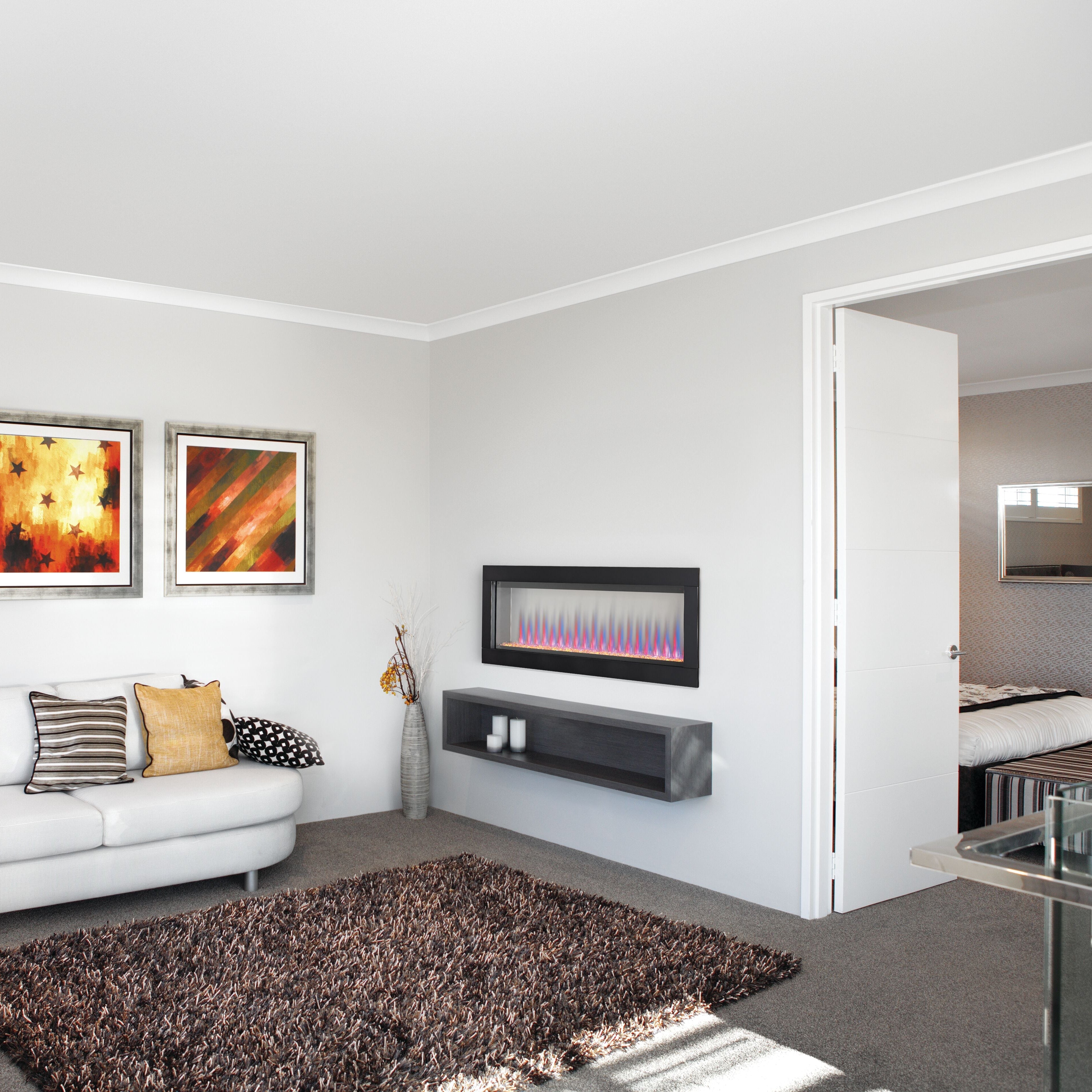 Modern living room with a white sofa, decorative pillows, and a wall-mounted electric fireplace.