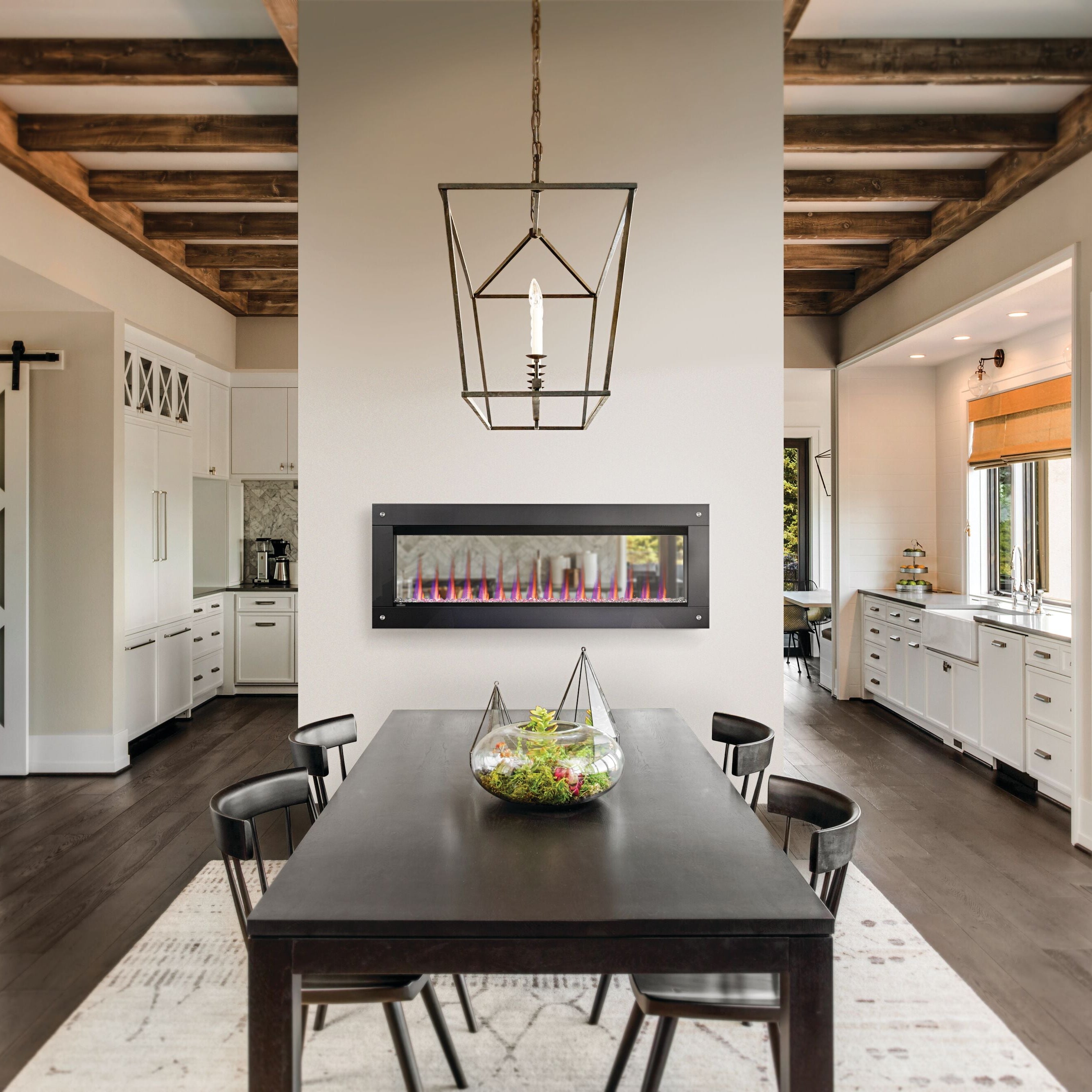 Modern dining room with wooden table and chairs, pendant light, and kitchen in the background.